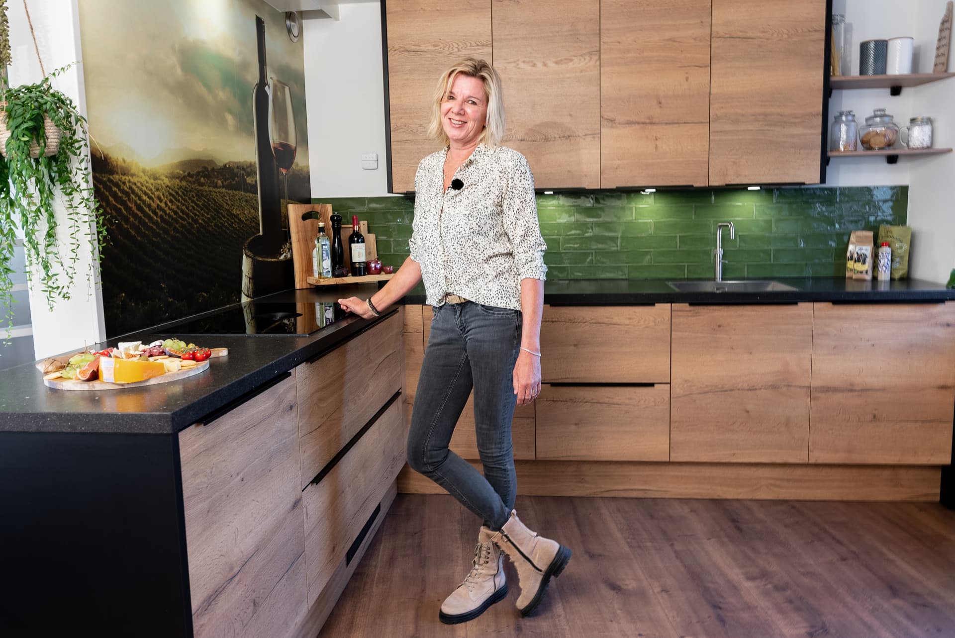 Houten hoekkeuken met groene wandtegels en zwart werkblad