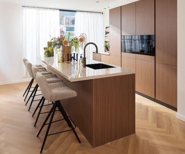 Donker houten keuken met hoge kasten en een kookeiland met bar
